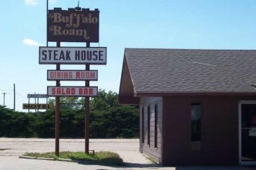 Sign for "Buffalo Roam" steakhouse featuring dining room and salad bar, with a motel in the background.