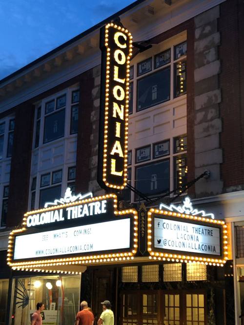 The illuminated marquee of the Colonial Theatre at dusk, featuring the name and upcoming events.