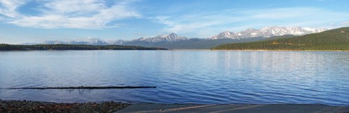 A serene lake surrounded by mountains under a clear blue sky, with gentle ripples on the water's surface.
