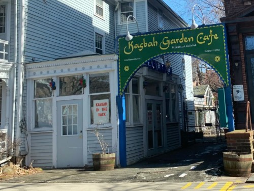 Entrance to Kaybah Garden Café, featuring a colorful sign and a small outdoor area, with a sign indicating "Kasbah in the back."