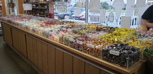 A colorful candy display with various types of sweets in clear bags, arranged neatly on a wooden counter.