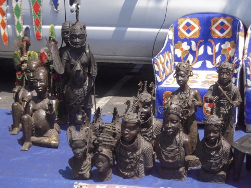 A collection of intricate bronze sculptures displayed on a blue cloth, featuring figures in traditional attire.