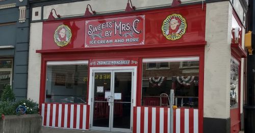 Brightly colored storefront of "Sweets by Mrs. C," featuring ice cream and more, with red and white striped accents.