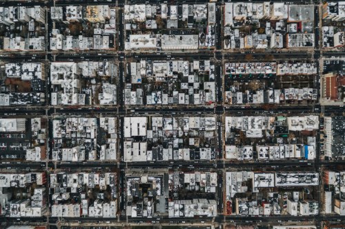 Aerial view of a city grid with densely packed buildings and streets, some covered in snow.
