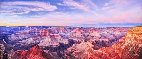 A panoramic view of the Grand Canyon at sunset, showcasing vibrant colors and layered rock formations.