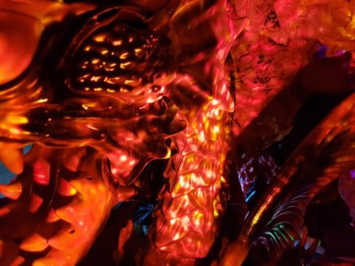Close-up of a colorful dragon sculpture with vibrant red and orange lighting, showcasing intricate details and textures.
