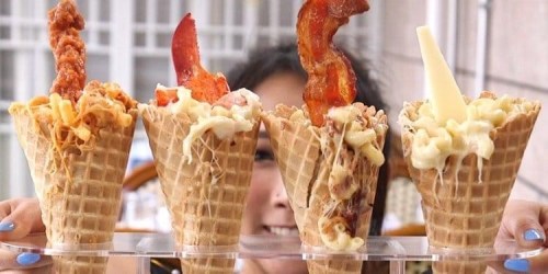 A person holds four ice cream cones filled with unique toppings, including bacon, macaroni, and cheese.