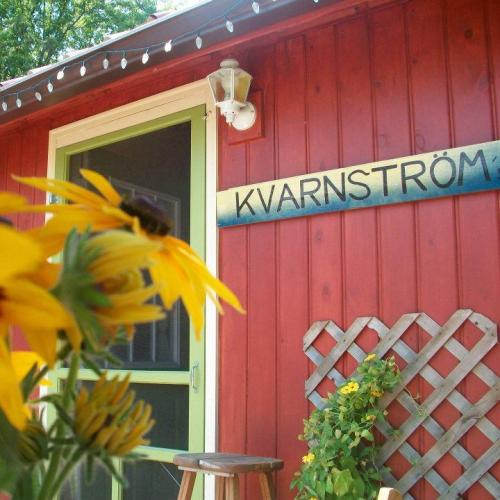 A red wooden building with a sign reading "Kvarnström" and yellow flowers in the foreground.