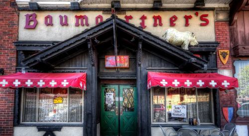 Front view of Baumertner's restaurant, featuring a cow statue, red awnings, and decorative signage.