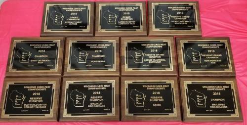 A collection of wooden plaques from the 2018 Wisconsin Cured Meat Championships, showcasing various awards and categories.