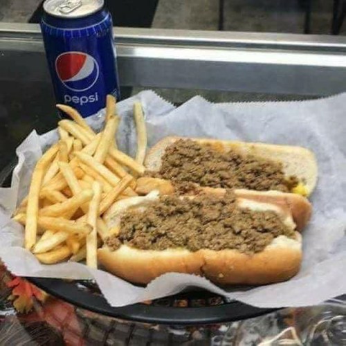 A plate with two hot dogs filled with meat, served with fries and a can of Pepsi.
