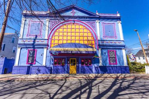 Colorful theater building with a large arched entrance, featuring purple and yellow accents and a gift store sign.