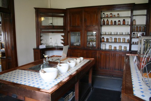 A vintage laboratory with wooden cabinets, glass containers, and bowls on a countertop, showcasing a historical setting.