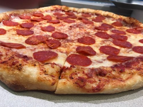 A freshly baked pepperoni pizza with a golden crust and melted cheese, sliced and ready to serve.