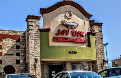 Exterior of Joy Wok restaurant featuring "Super Buffet & Hibachi Grill" sign, with cars parked in front.