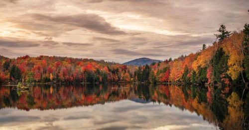 The fall foliage near a lake with a mountain in the background at Killington, Vermont