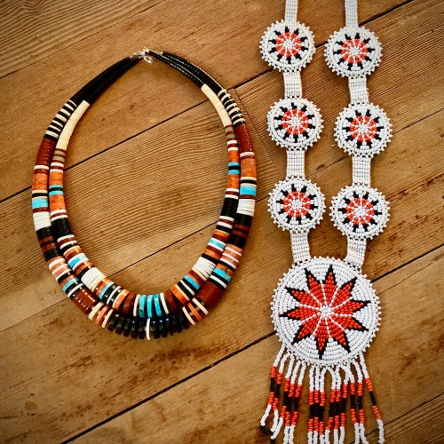 Colorful beaded necklaces displayed on a wooden surface, featuring intricate patterns and vibrant colors.