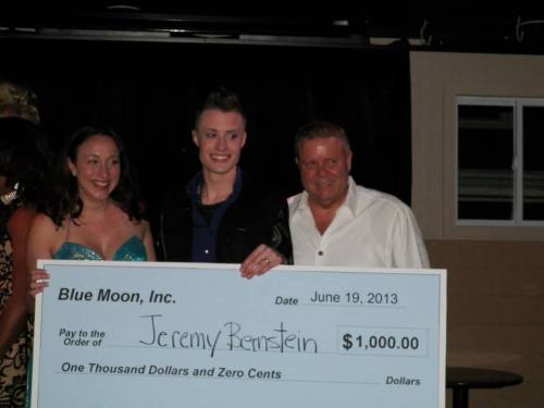 A group poses with a large check for $1,000, celebrating an award or donation at an event.