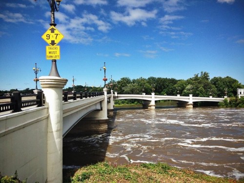 A bridge over a river with a warning sign for height restrictions and clear blue skies in the background.
