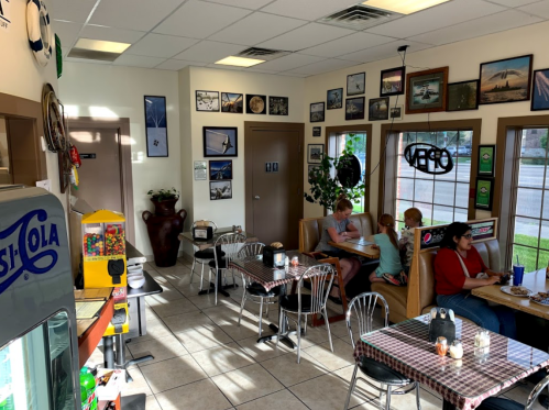 A cozy diner with booths, tables, and walls adorned with photos, featuring patrons enjoying their meals.