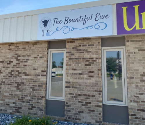 Sign for "The Bountiful Eve" on a brick building, featuring a sheep graphic and decorative lettering.