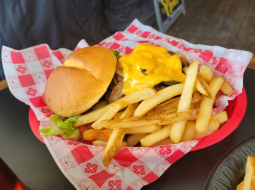 A basket with a cheeseburger topped with melted cheese, lettuce, and a side of golden French fries.