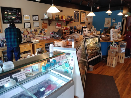 A cozy café interior with a display case, wooden counters, and customers enjoying the space.