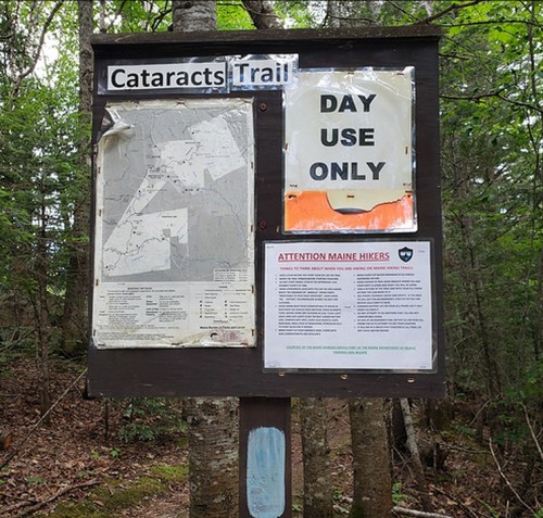 Signpost for Cataracts Trail featuring a map, "Day Use Only" notice, and hiker guidelines in a wooded area.