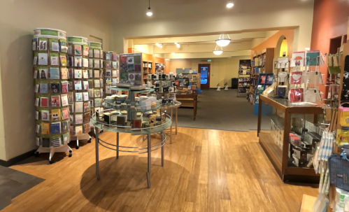 A spacious store interior featuring card displays, shelves of products, and wooden flooring.
