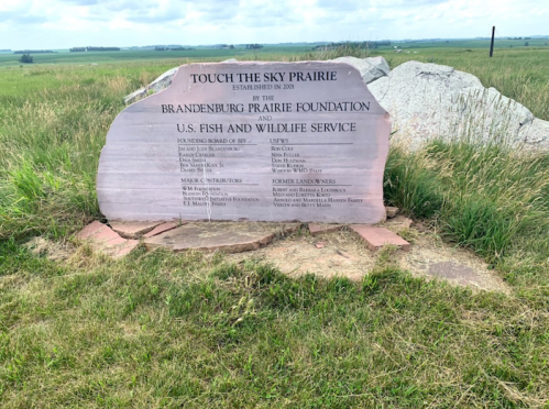 A stone monument for Touch the Sky Prairie, established in 2001, listing contributors and partners in conservation efforts.