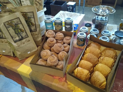 A table displaying baked goods, including cinnamon rolls and croissants, alongside coffee and tea products in bags.