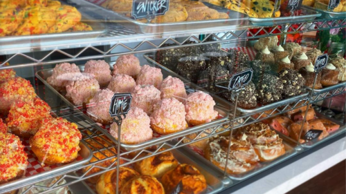 A display case filled with colorful pastries, including pink frosted treats and various baked goods.