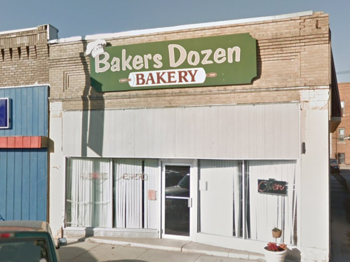 Front view of "Bakers Dozen Bakery" with a green sign, large windows, and an "Open" sign displayed.