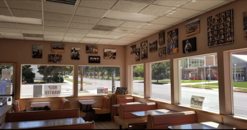Interior of a closed restaurant with empty booths, large windows, and walls adorned with framed photos.
