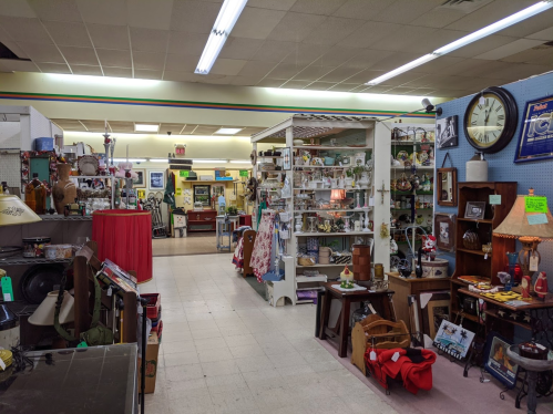 A spacious antique store filled with various vintage items, furniture, and decor displayed on shelves and tables.
