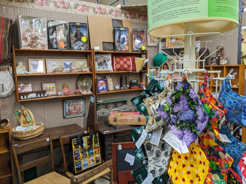 A cozy vintage shop display featuring shelves of eclectic items, including decor, fabrics, and collectibles.
