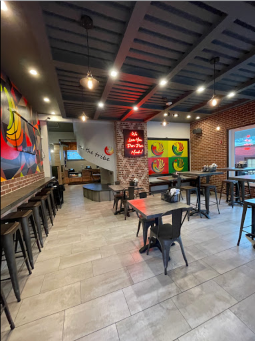 Interior of a modern restaurant featuring colorful wall art, wooden tables, and industrial-style lighting.