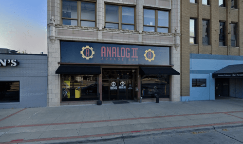 Exterior of Analog II Arcade Bar, featuring a large sign and a welcoming entrance, set in an urban environment.