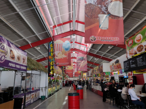 A vibrant indoor market with food stalls, colorful banners, and people enjoying various cuisines.