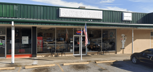 A storefront of Baker's Pride with an open sign, outdoor seating, and an American flag in front.