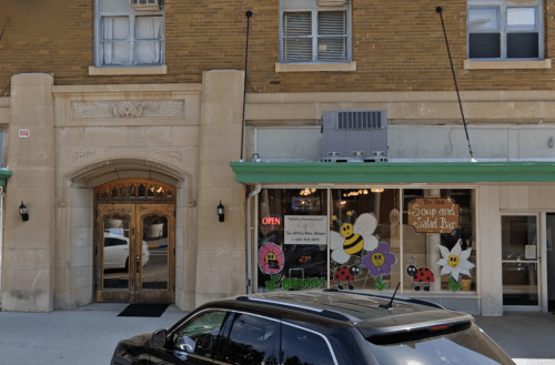 Exterior view of a building featuring a soup and salad bar with colorful flower and insect decorations.