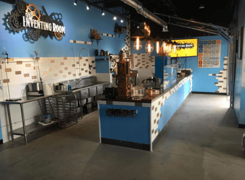 Interior of a modern kitchen with blue walls, industrial decor, and a counter displaying various kitchen equipment.