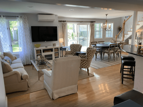 Bright, open living space with a cozy seating area, dining table, and large windows overlooking a garden.