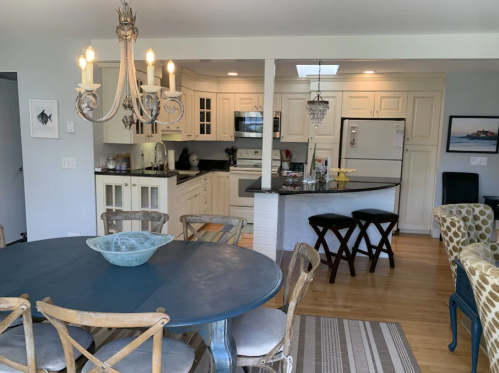 A bright kitchen and dining area featuring a round table, chandelier, and modern appliances in a cozy setting.
