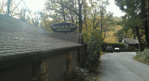 Sign for "Louie's on the Lake Restaurant" beside a winding road surrounded by trees in autumn.
