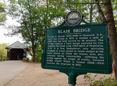 Historic Blair Bridge in New Hampshire, built in 1829, with a sign detailing its history and restoration.