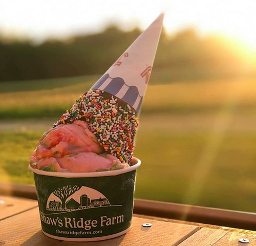 A colorful ice cream cone topped with sprinkles, set against a sunset backdrop at Shaw's Ridge Farm.