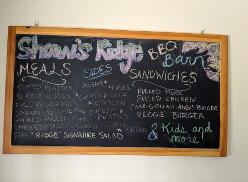 Chalkboard menu for Shawn's Ridge BBQ Barn featuring meals, sides, and sandwiches like pulled pork and veggie burger.