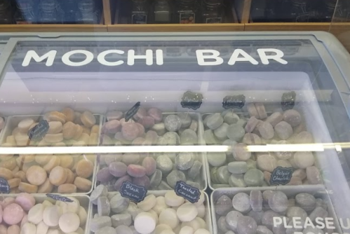 A display case labeled "Mochi Bar" filled with various colorful mochi desserts.