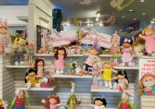 A colorful display of dolls in a shop, featuring a sign that reads "Welcome to Baby Land" and various themed decorations.